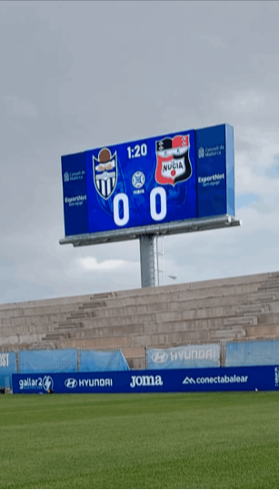 Cartel retroiluminado de marcador de campo de futbol sobre las gradas realizado en colores azules y con tecnología LED para máxima visibilidad tanto de día como de noche.