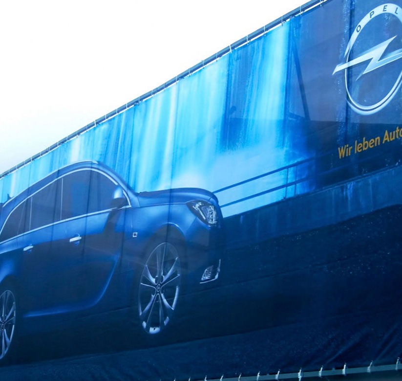 "Lona publicitaria de gran formato con impresión de alta calidad, resistente a la intemperie.