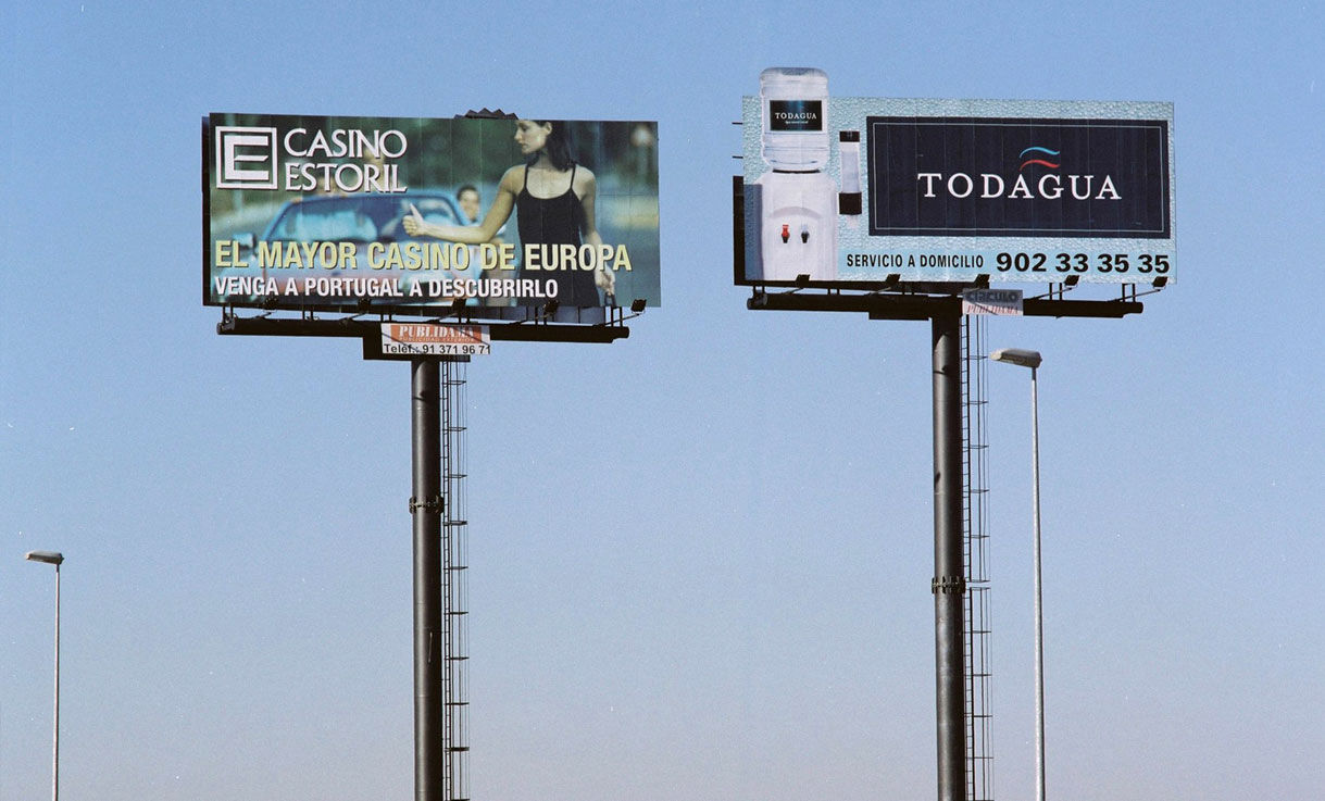 Monopostes publicitarios dobles con anuncios de Casino Estoril y Todagua, diseñados para garantizar máxima visibilidad en carretera.