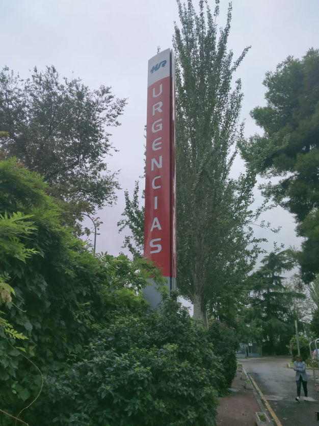 "Poste publicitario retroiluminado con señalización vertical de 'Urgencias', diseñado para alta visibilidad en entornos hospitalarios."